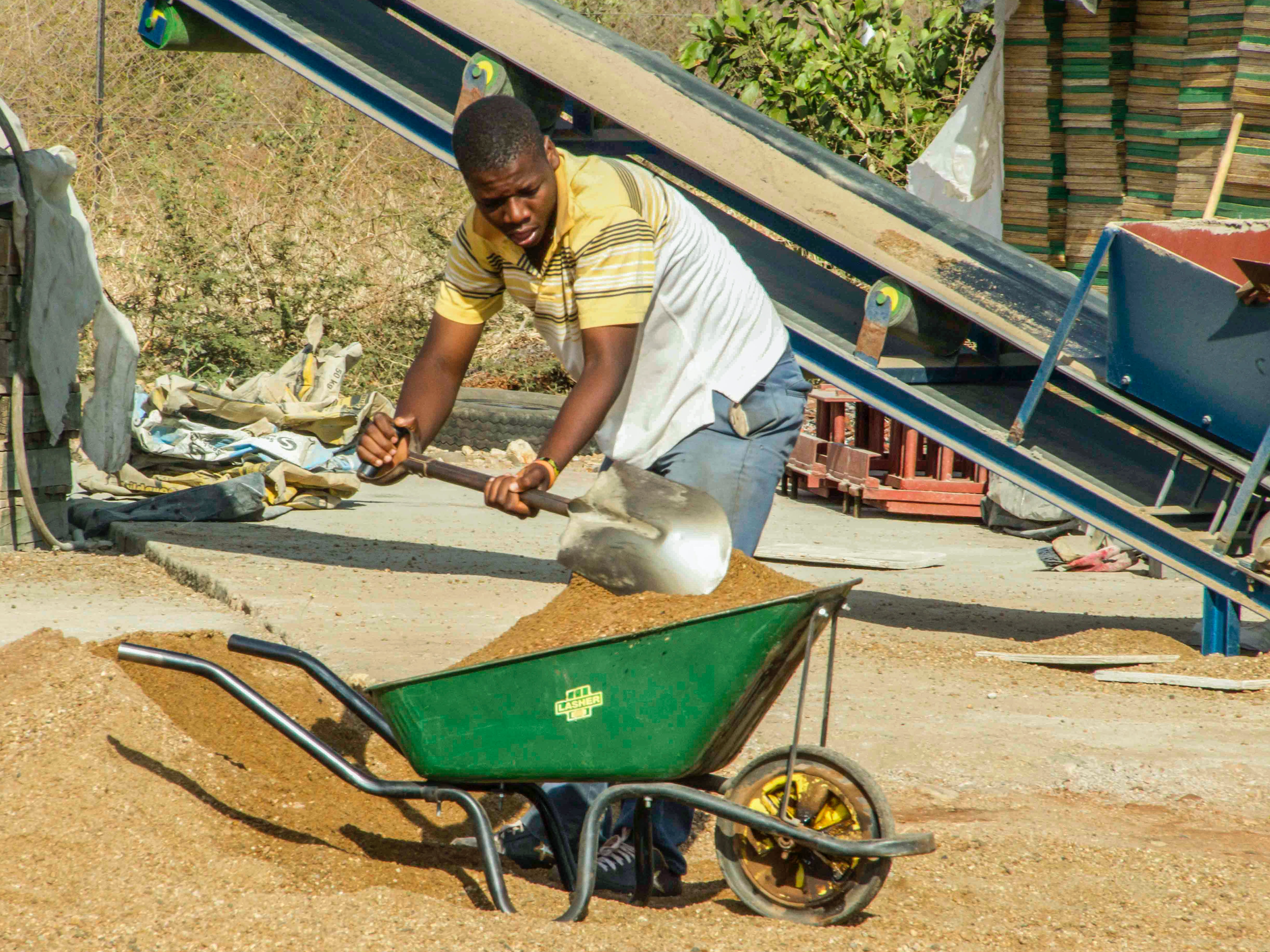 man filling wheelbarrow with sand